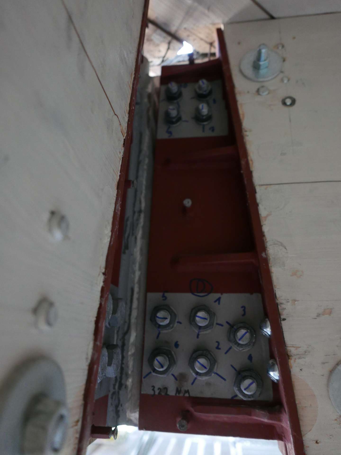 Eine veraltete elektrische Schaltanlage mit Drehrschaltern in einem roten Metallgehäuse an einer weißen Hauswand.