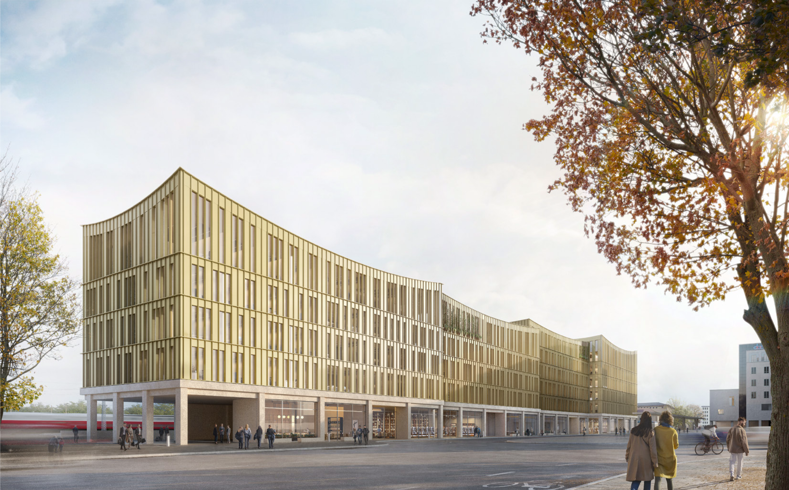 Ein modernes Gebäude mit charakteristischer goldener Metallfassade und offener Erdgeschosszone prägt einen urbanen Platz im Herbst.