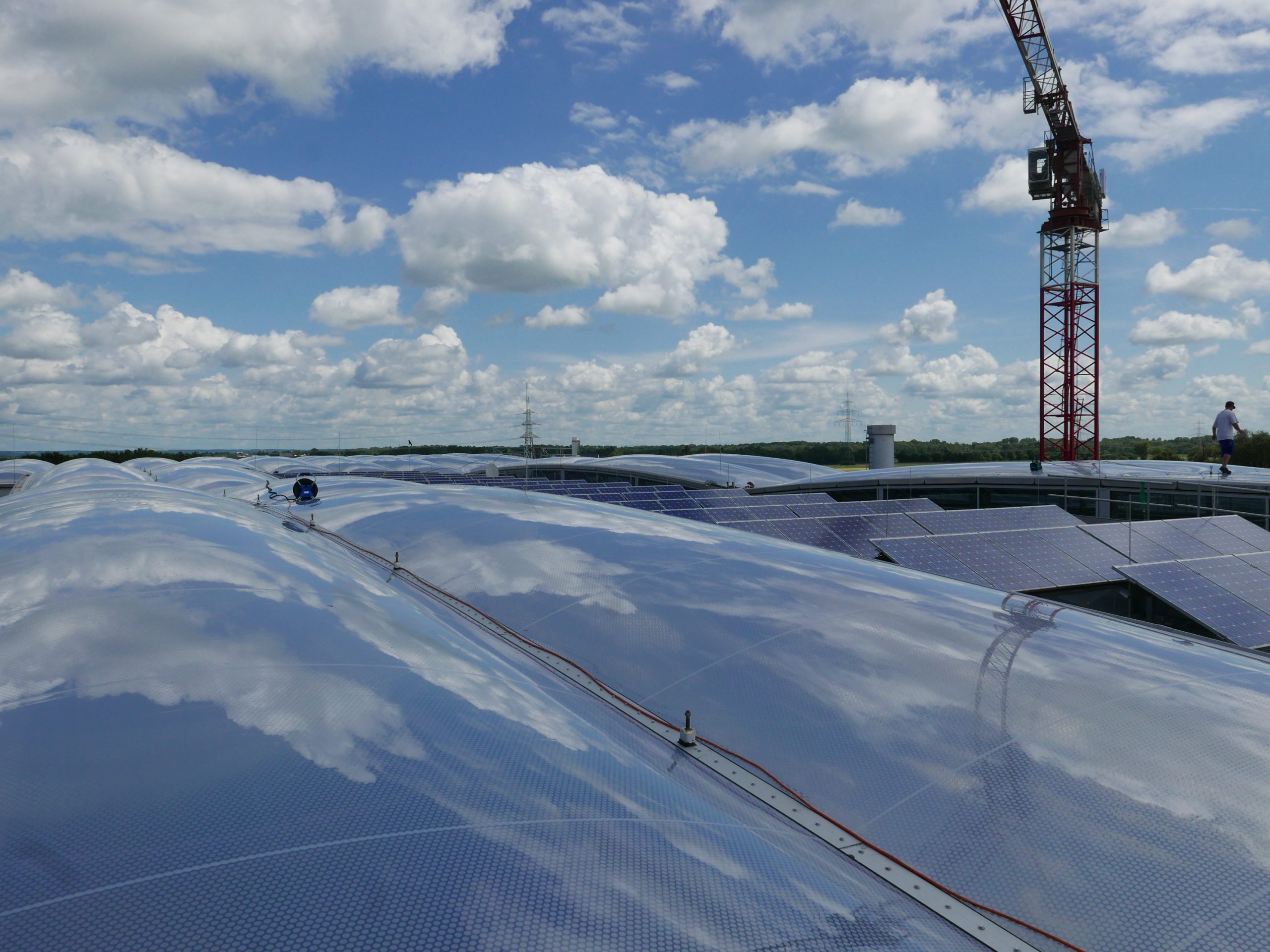 Auf einem großen Flachdach erstreckt sich eine moderne Solaranlage mit zahlreichen Photovoltaikmodulen unter einem bewölkten Himmel.