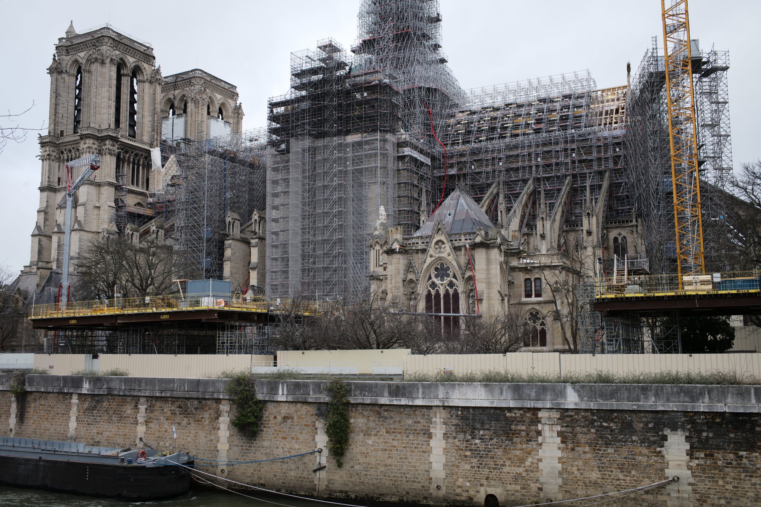 Notre-Dame de Reims im Wiederaufbau mit Gerüsten und Kränen, umgeben von Schutzwänden an der Seine.