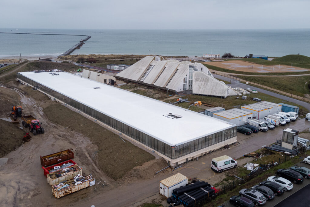 Luftaufnahme eines modernen Gebäudekomplexes an der Küste während der Bauphase.