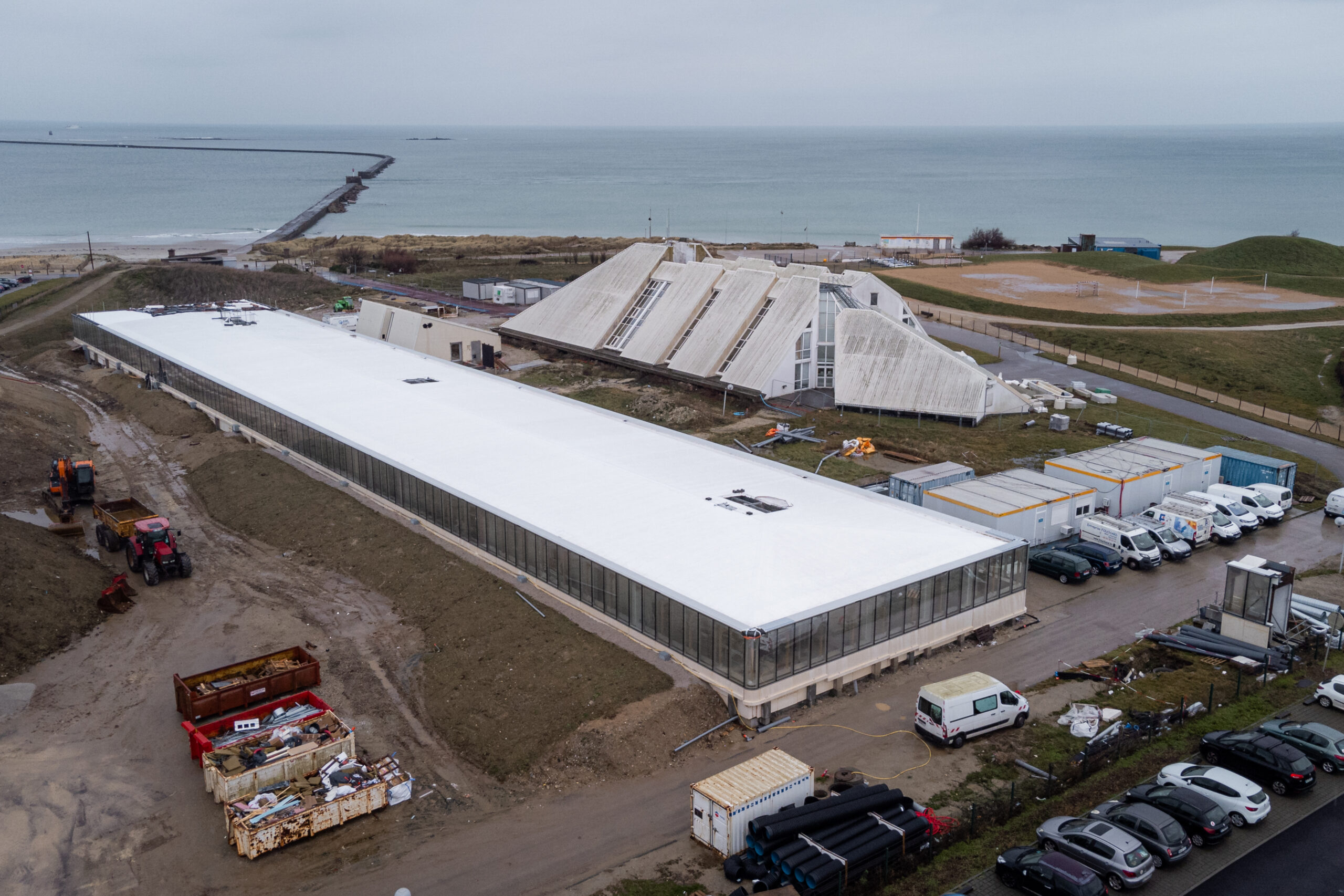 Luftaufnahme eines modernen Gebäudekomplexes an der Küste während der Bauphase.